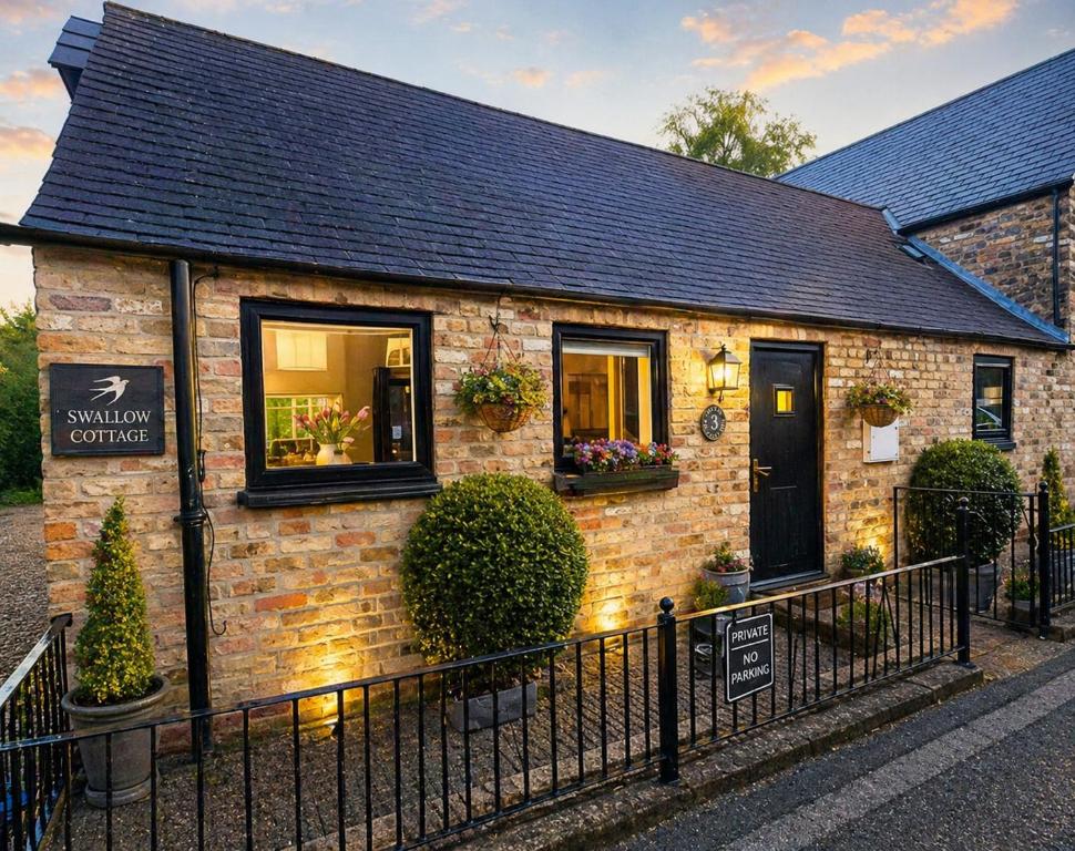 a brick house with a black door on a street at Swallow cottage in Howden