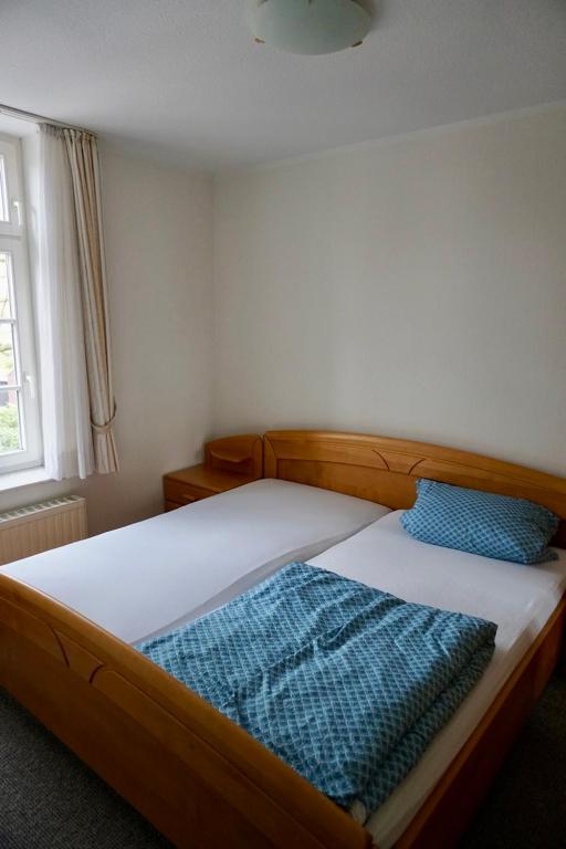 a bedroom with a bed with two blue pillows on it at Hotel zum Freiheiter Hof in Raesfeld
