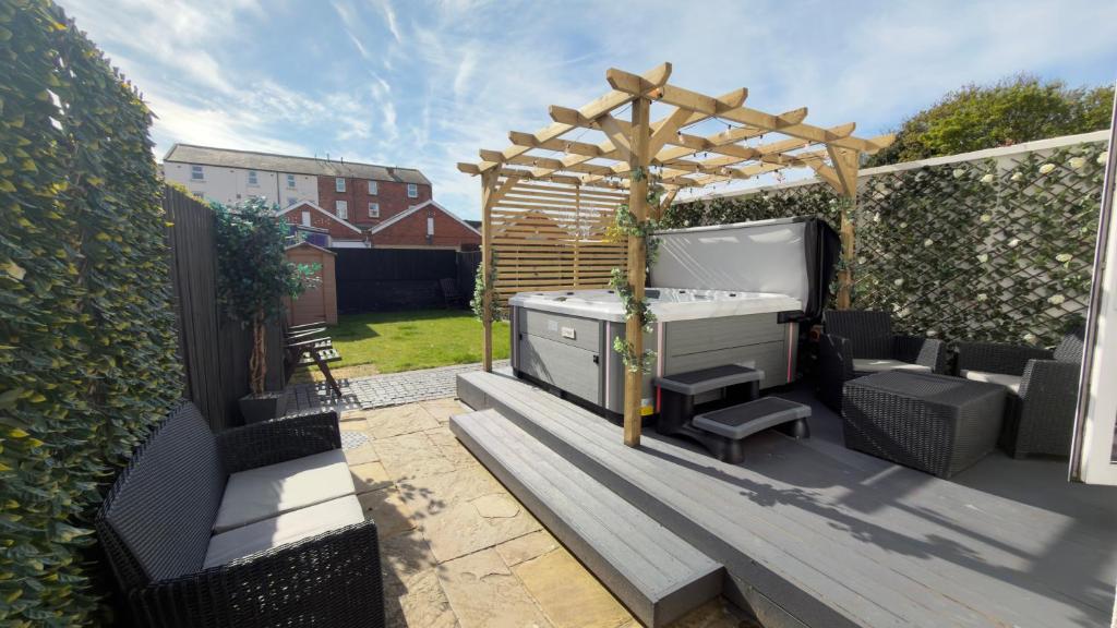 a backyard with a grill and a wooden pergola at Lethbridge Villa 49 3-bedroom Apartment with private HOT TUB,Fibre WiFi, free parking, sleeps 6 in Southport