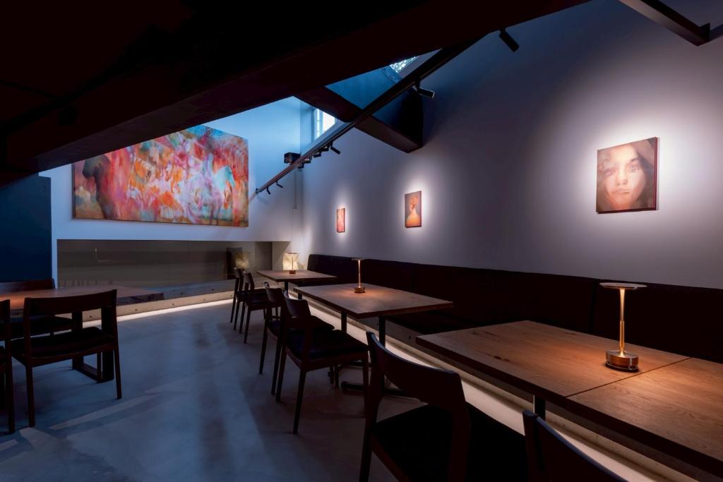 a row of tables in a restaurant with a painting on the wall at Experience Ise Miyamachi Hotel in Ise