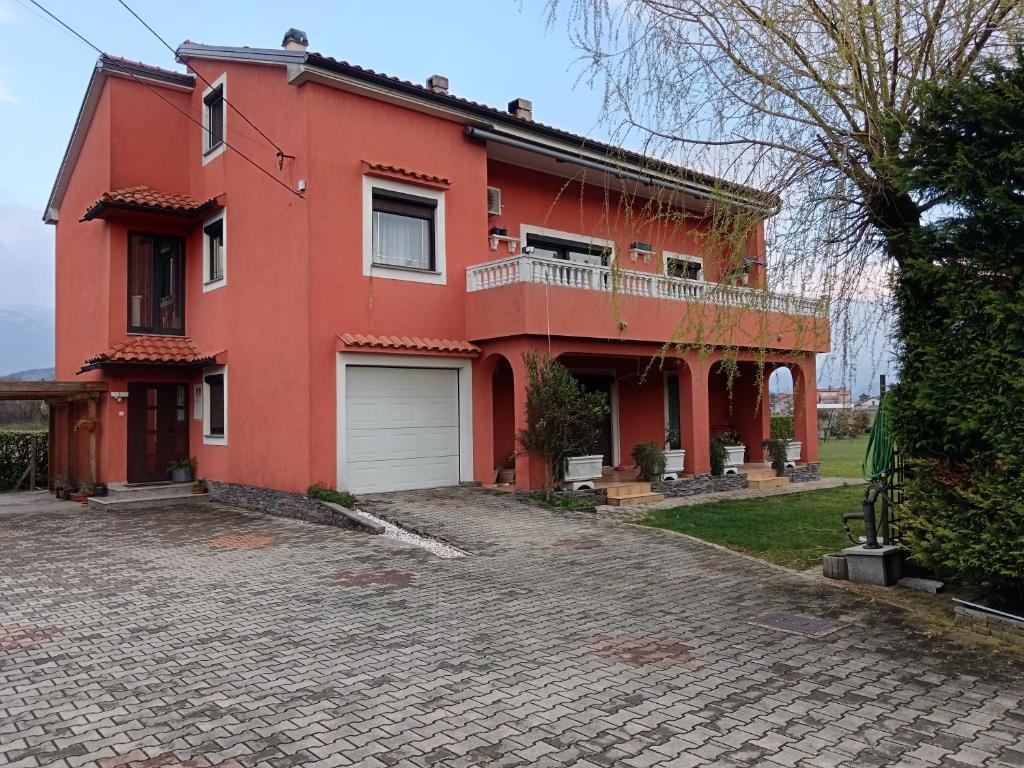 a red house with a driveway in front of it at Mirni krov in Dražice