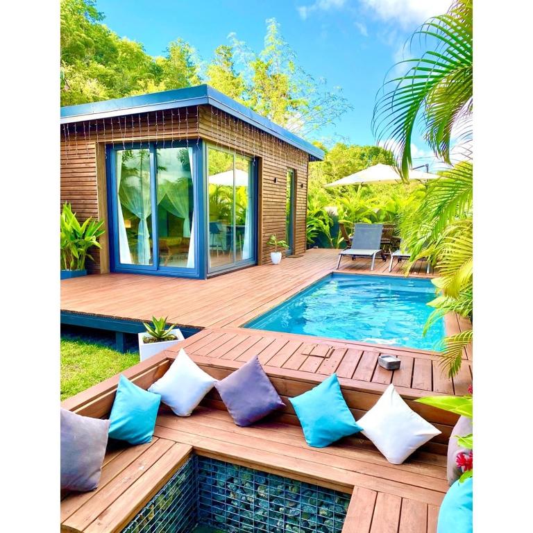 a deck with a pool and a house at Moderne Lodge Tropical in Les Abymes