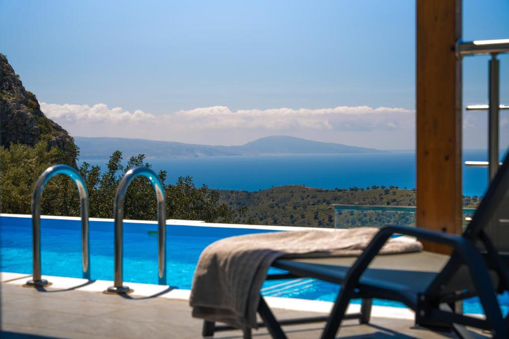 a chair sitting on a balcony with a view of the ocean at Vrachos Nature Lodges Thyme 1, Private pool in Agia Galini