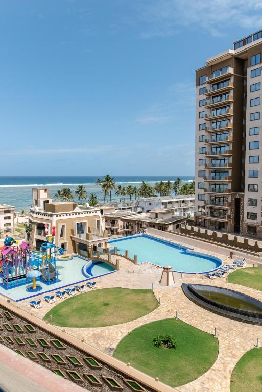 a view of the pool at the resort with the ocean in the background at Sandy Shore Beach Apartments - Karibu Quarters in Kikambala