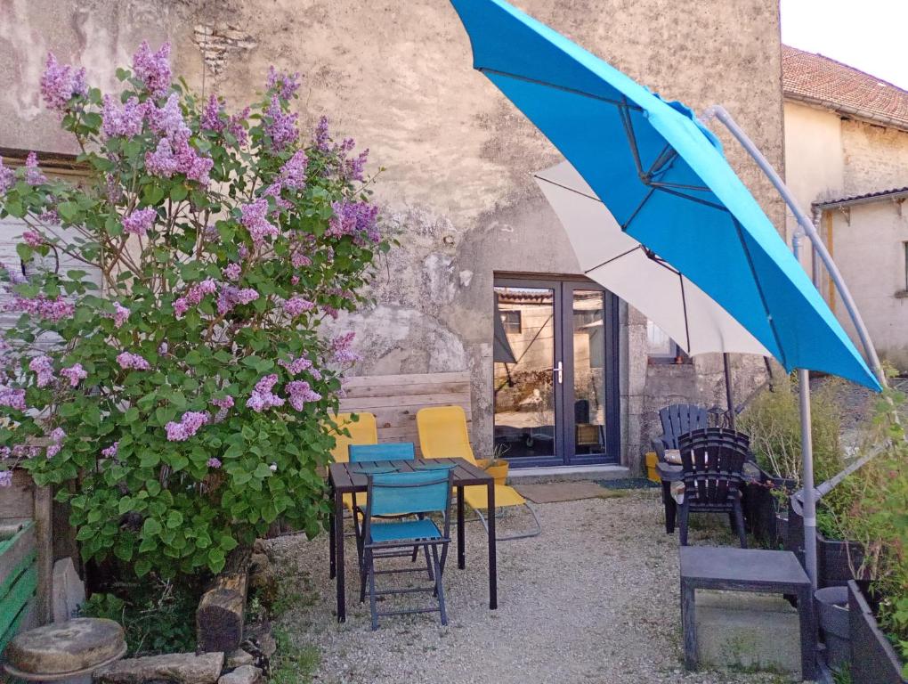 a patio with chairs and a table and an umbrella at Au jeu de mots, chambre d'hôtes proche Poligny in Barretaine