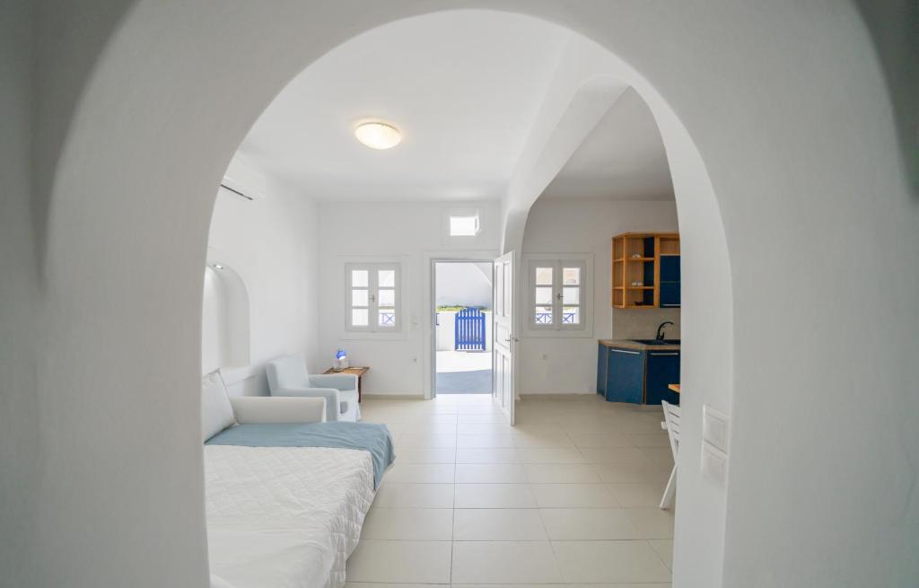a white living room with a couch and a kitchen at Coastal Escape - 2 min from Perissa Beach in Perissa