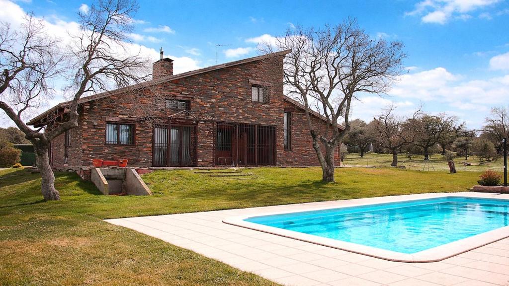 a brick house with a swimming pool in front of it at Casa Pirinea, Maello, Avila in Maello