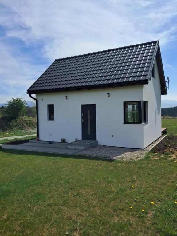 a white house with a black roof on a field at Reset w górach in Ponikwa