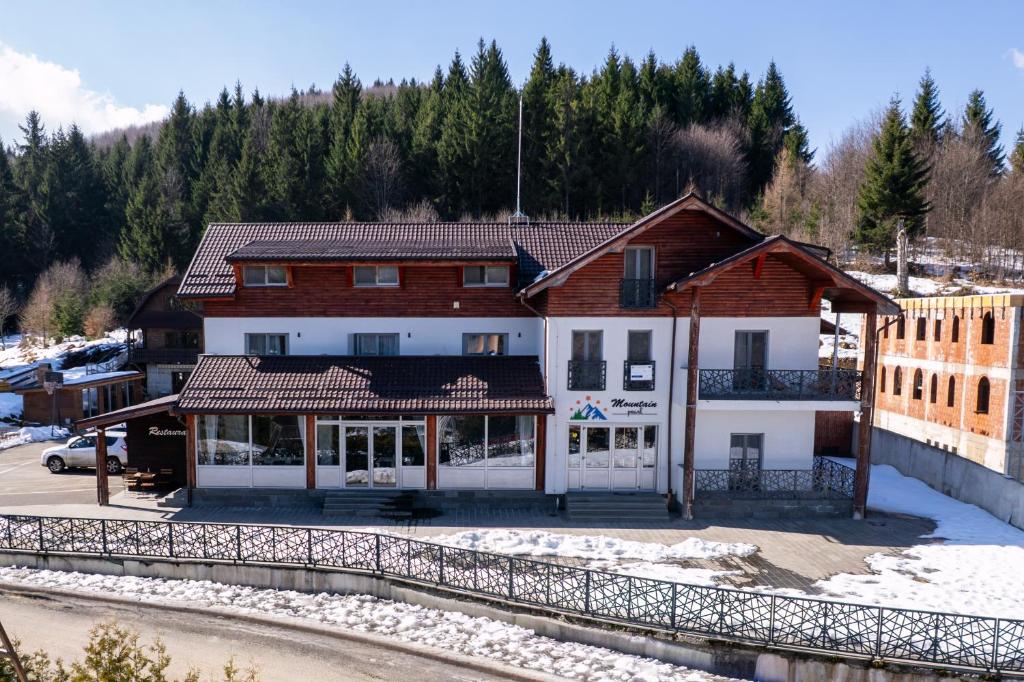 a building in a town with snow on the ground at Pensiunea Mountain Pearl in Deseşti