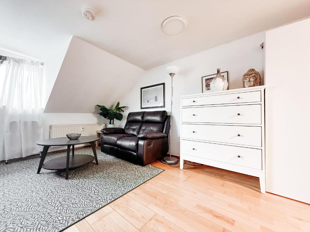 a living room with a leather chair and a dresser at SkyNest Pirna gemütliches Dachstudio mit Stadtblick in Pirna