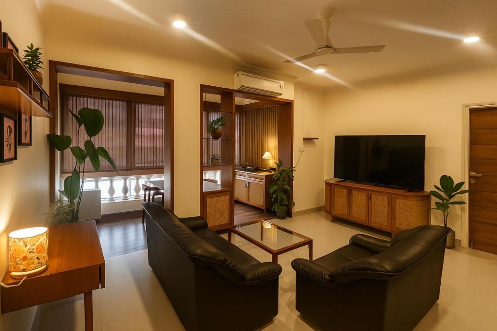a living room with two leather chairs and a flat screen tv at Cairo in Siolim