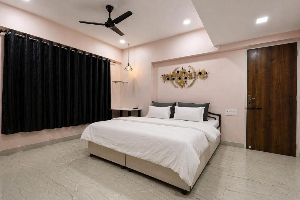 a bedroom with a large bed with a ceiling fan at StayLuxe Rooms & Apartments Near BKC, Chembur in Mumbai
