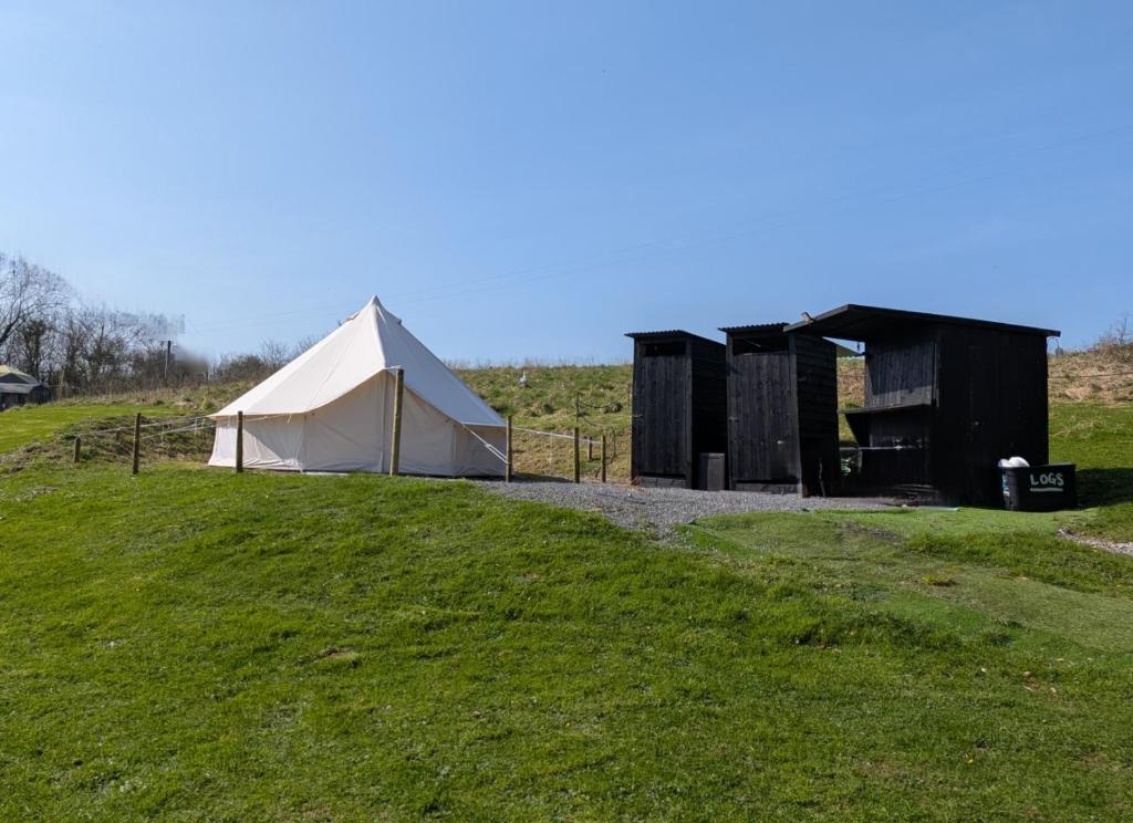 a tent on a grassy hill next to a field at Private Luxury Glamping surrounded by wildlife in Pembrokeshire