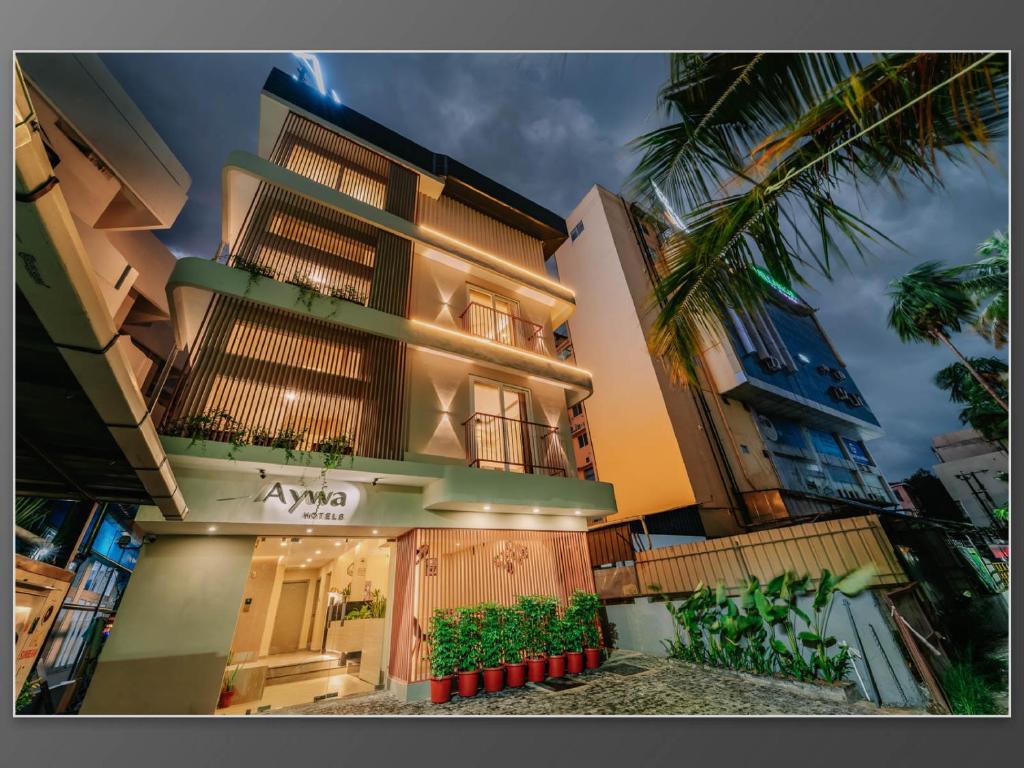 a building with a palm tree in front of it at Aywa Hotels Edapally in Cochin