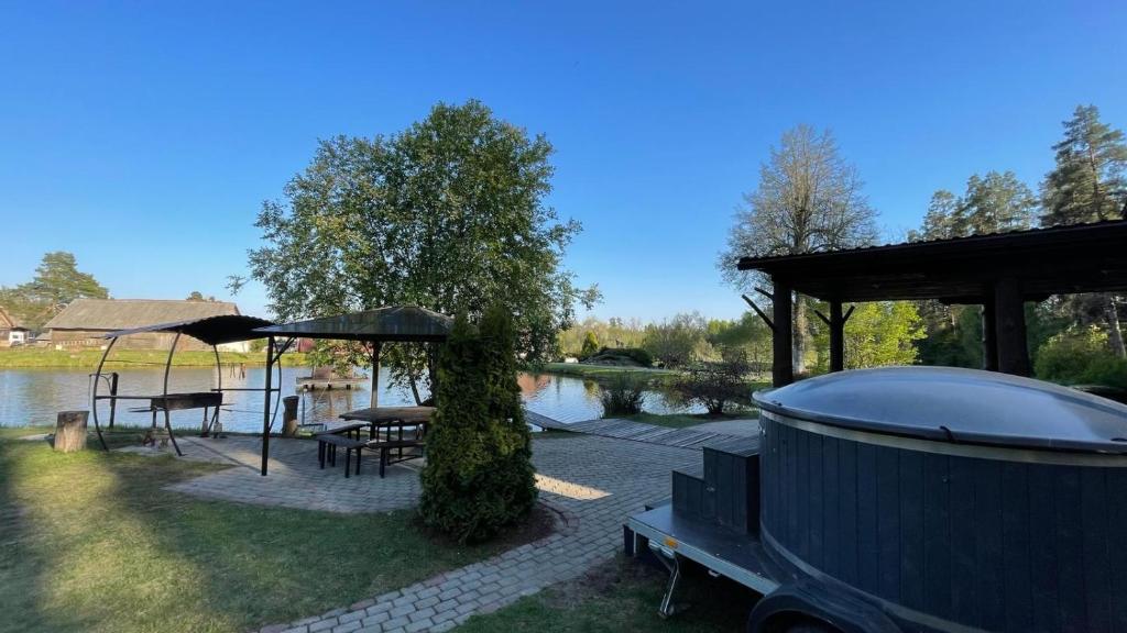 eine Terrasse mit Pavillon neben einem See in der Unterkunft Lejupes in Plānupe