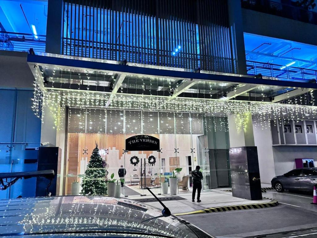 a man walking in front of a building with christmas lights at Polished Studio at The Verdin Maple Grove in General Trias