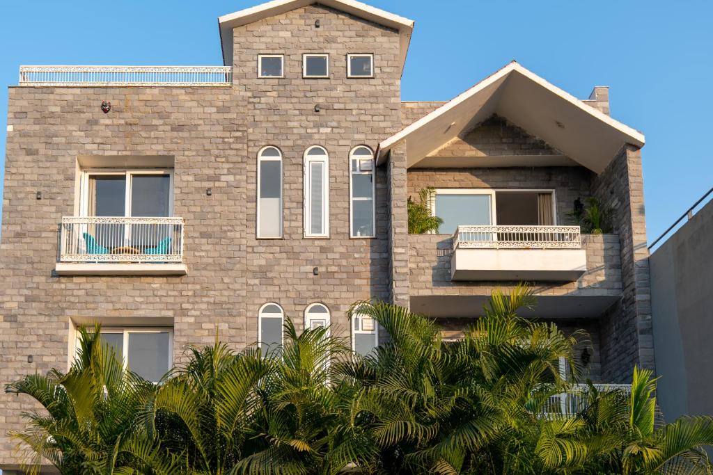 a brick building with a balcony and palm trees at Jolawas Stays Udaipur in Udaipur