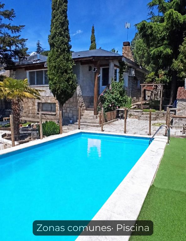 a blue swimming pool in front of a house at La Consentida in La Cabrera