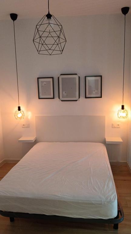 a bedroom with a bed with three pictures on the wall at SG Estudios Sanlúcar in Sanlúcar de Barrameda