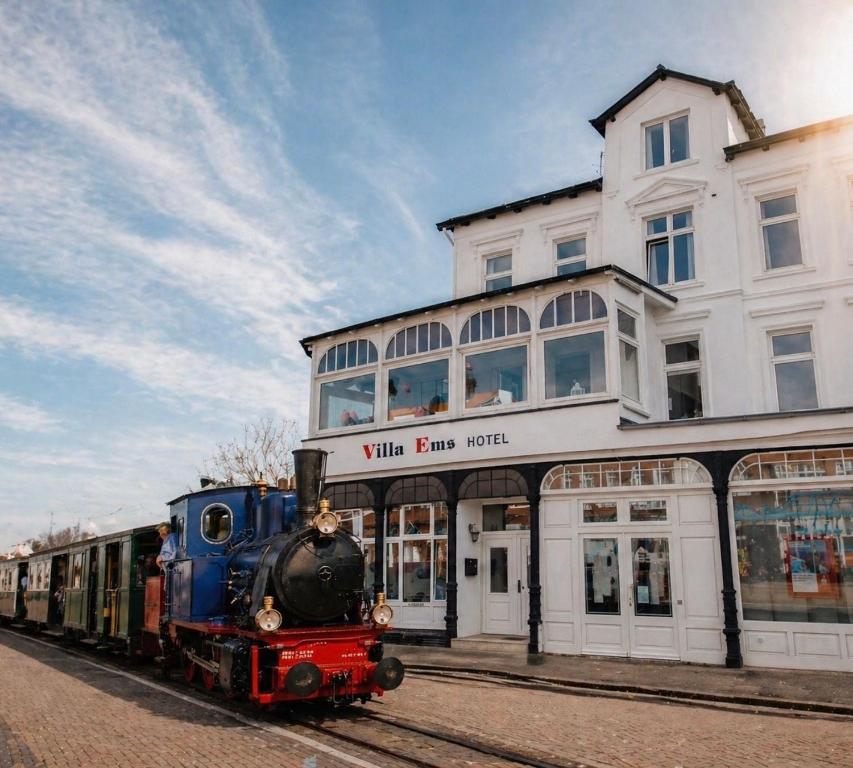 a train on the tracks in front of a building at Hotel Villa Ems in Borkum