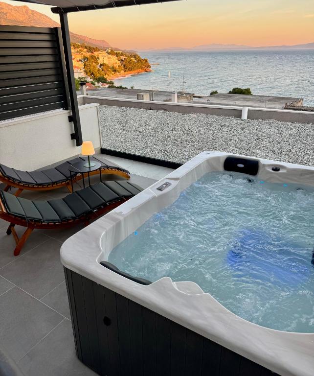 a hot tub and a chair on a balcony with the ocean at Apartments Lusi in Brela