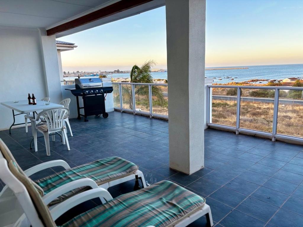 a balcony with a table and a piano and the ocean at Wild Thyme in St Helena Bay in West Point