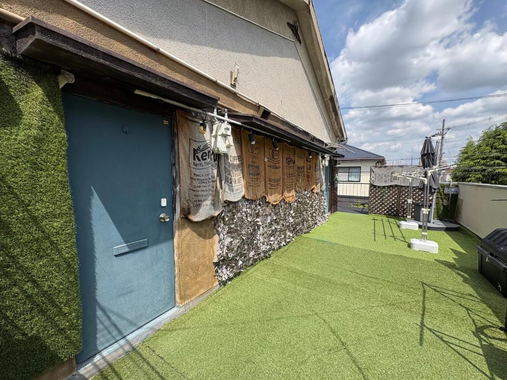 a blue door on a house with a green lawn at Layover Osaka-Kyoto in Fukui
