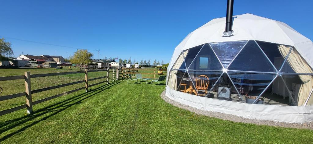 a dome tent in a field next to a fence at alpaca view Dome in New Holland