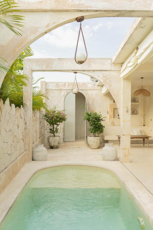 an outdoor swimming pool in a house with an archway at CASA NARA BALI in Canggu