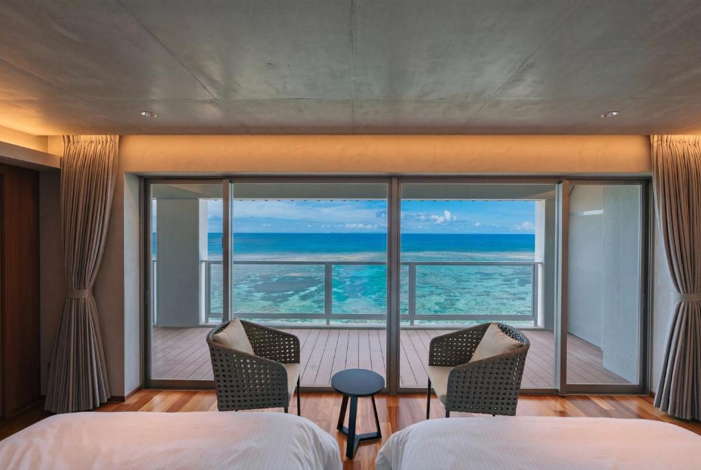 a bedroom with two beds and a view of the ocean at RAV RESORT Okinawa in Yomitan