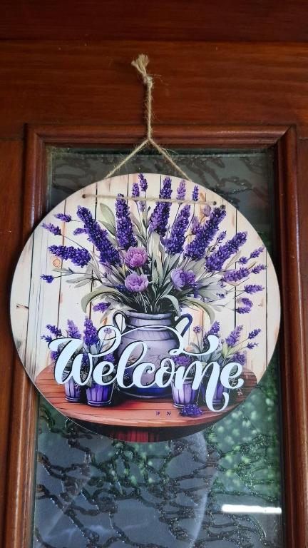a sign that says welcome with purple flowers in a vase at Apartman Lavanda in Temerin