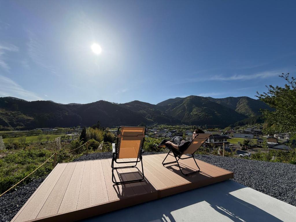 two chairs on a deck with a view of the mountains at 近露の家 -chikatsuyunoie- in Tanabe