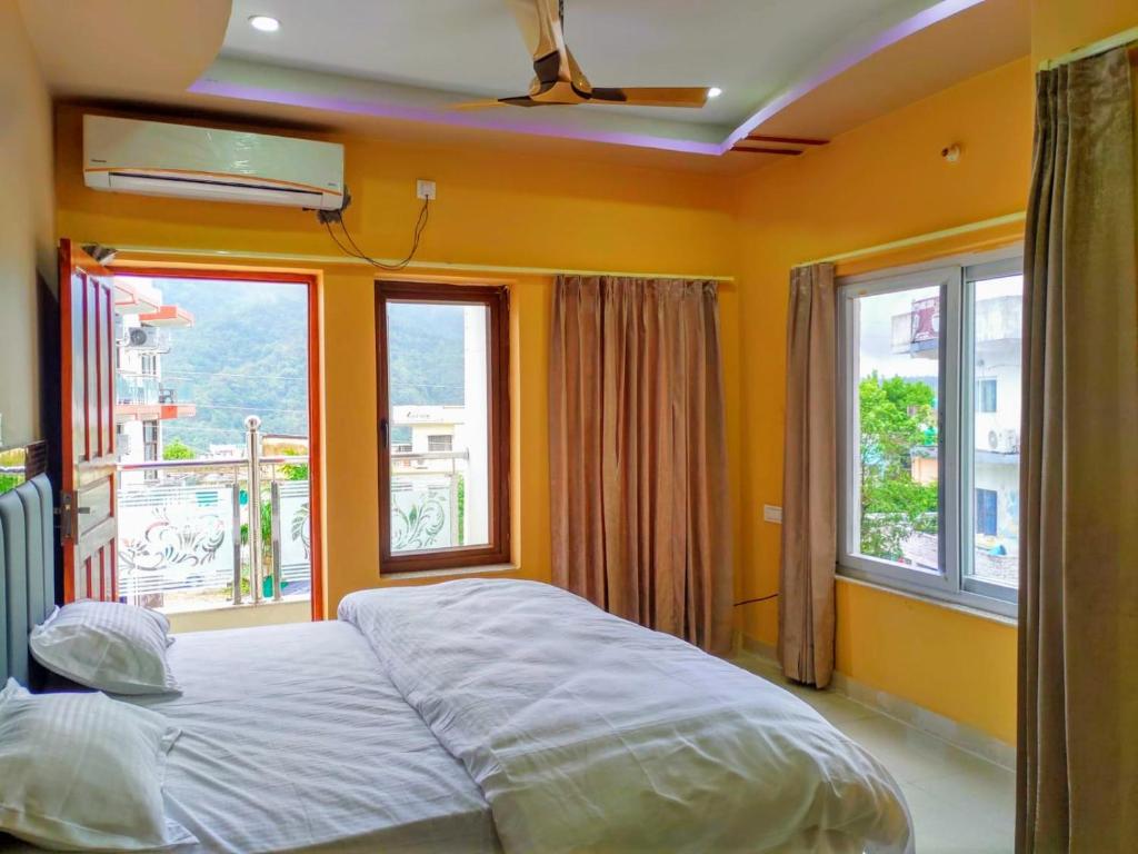 a bedroom with a bed and two windows at Mahadevs Mansion in Rishīkesh