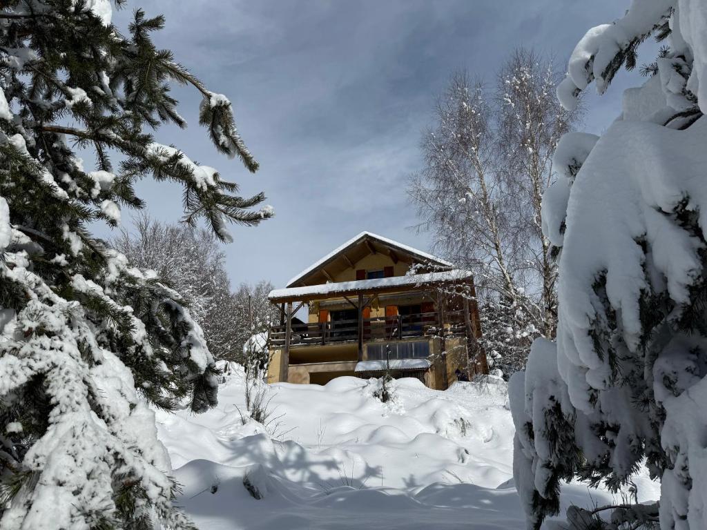 a log cabin in the snow with snow covered trees at Chalet confort avec cheminée in Camprieu