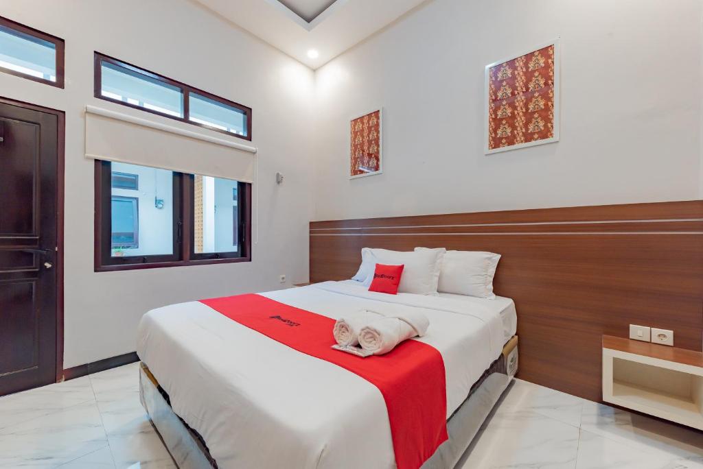 a bedroom with a large bed with a red blanket at RedDoorz Plus at Orange Diponogoro Palangkaraya in Palangkaraya