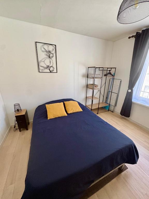 a bedroom with a large blue bed with yellow pillows at Pause Confort Studio idéal centre ville in Gravelines