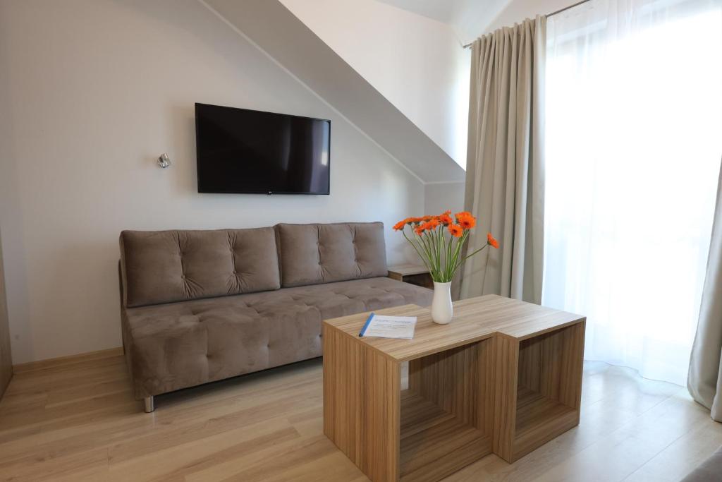 a living room with a couch and a table with flowers at Apartamenty Zdrojowa in Świnoujście