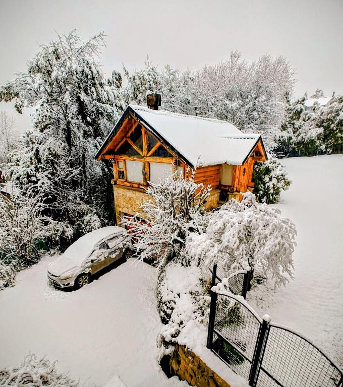 a house covered in snow with a car parked next to it at Blue Bird House in San Carlos de Bariloche
