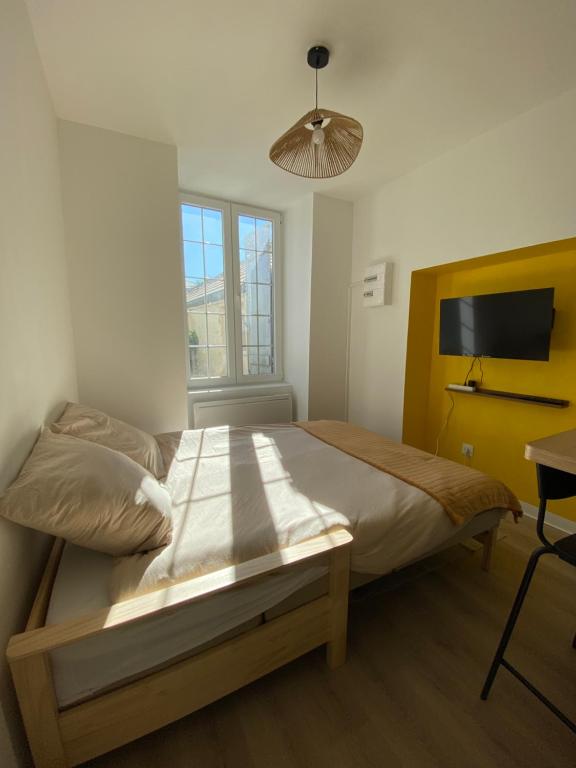 a bedroom with a bed and a desk and a window at Studio cosy avec jardin privé - Proche de tout ! in Montbard