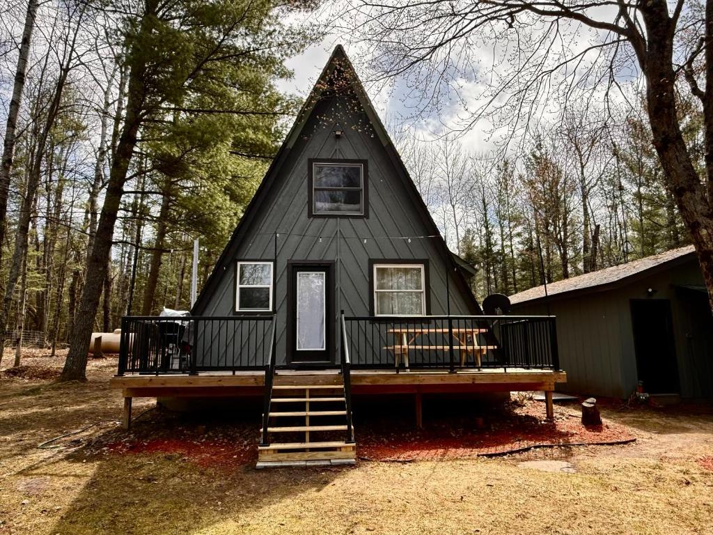 a small black house with a porch and stairs to it at Emerald Escape in Grayling