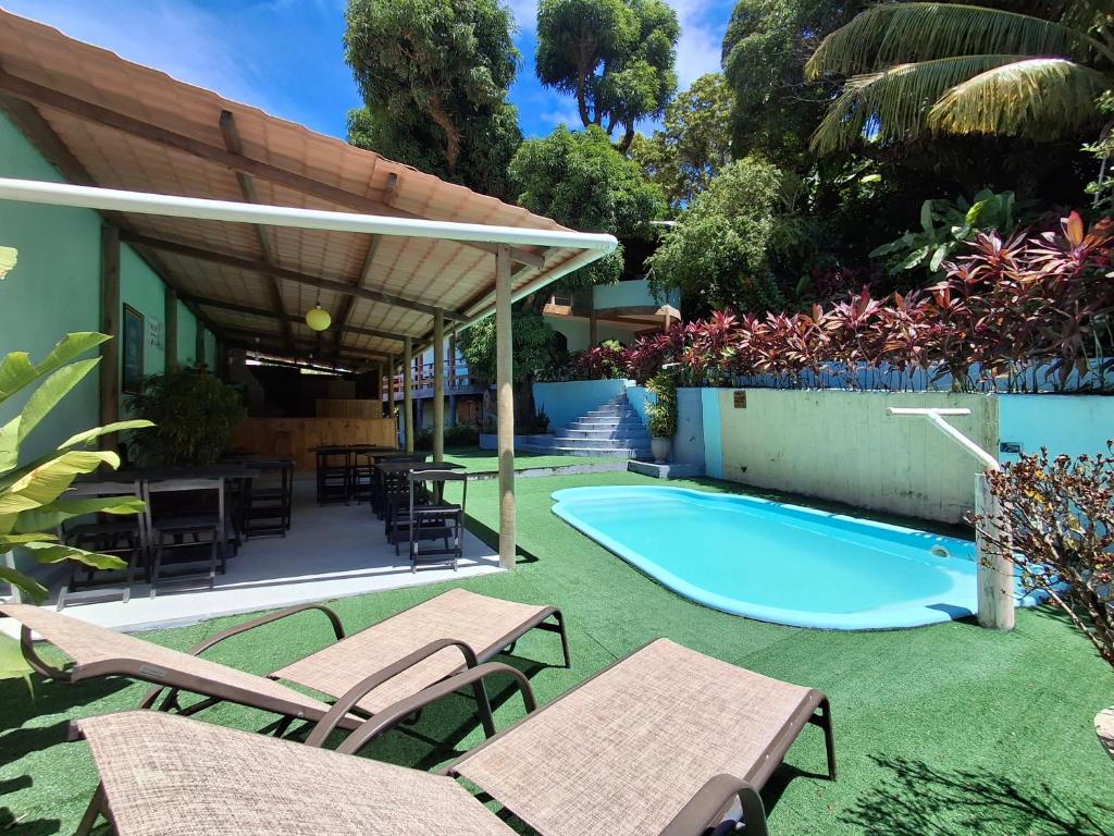 a patio with tables and chairs and a swimming pool at Beleza Natural Pousada in Morro de São Paulo
