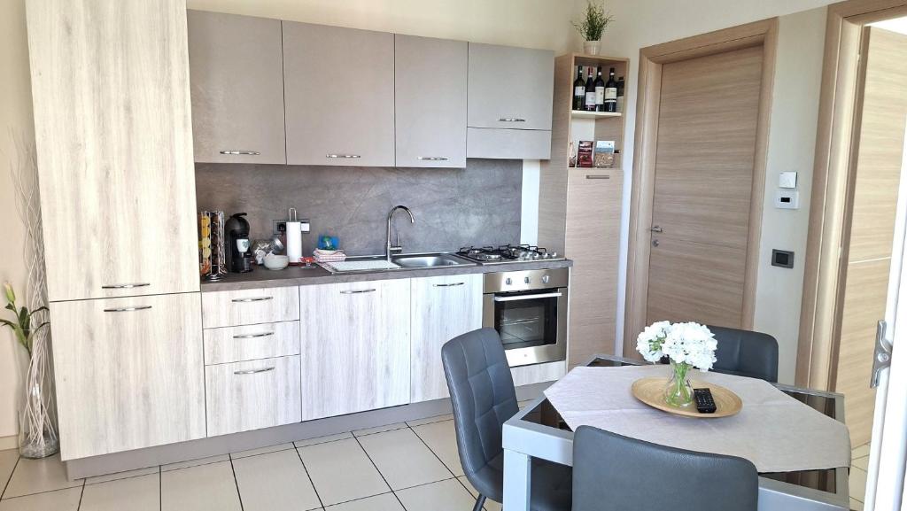 eine Küche mit weißen Schränken und einem Tisch sowie ein Esszimmer in der Unterkunft La trifula bianca apts. in Alba