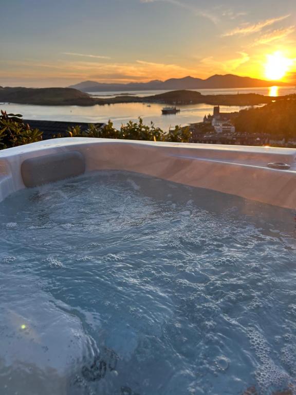 a hot tub with the sunset in the background at Tigh Beag Pod with Hot Tub in Oban