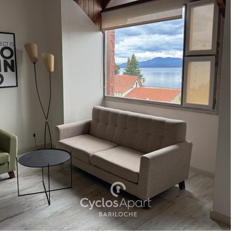 a living room with a couch and a large window at CyclosApart Bariloche in San Carlos de Bariloche