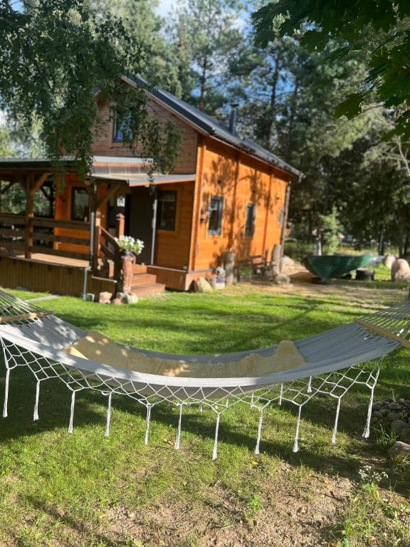 a hammock in the grass in front of a house at Dom nad Saskiem 3 sypialnie, jacuzzi-relaks, natura i komfort in Linowo