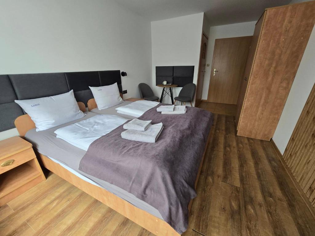a bedroom with a large bed with two towels on it at Dom Wczasowy Larix in Rewal