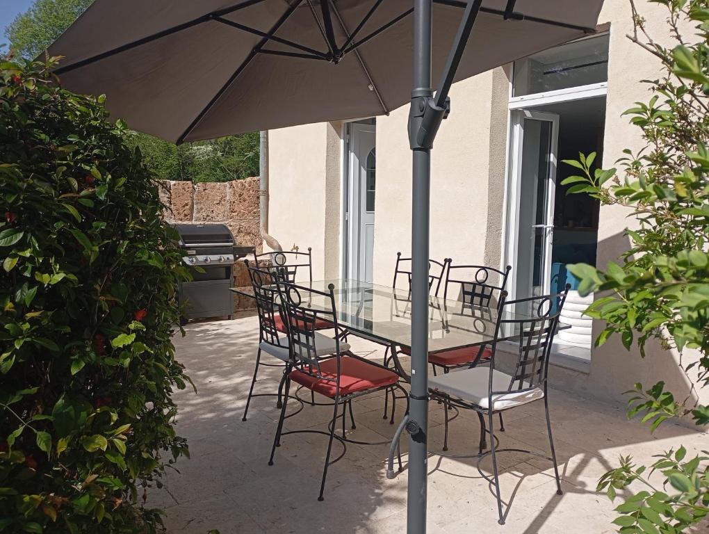 a glass table and chairs under an umbrella on a patio at Gite La maison du gardien in Marcillac-Vallon