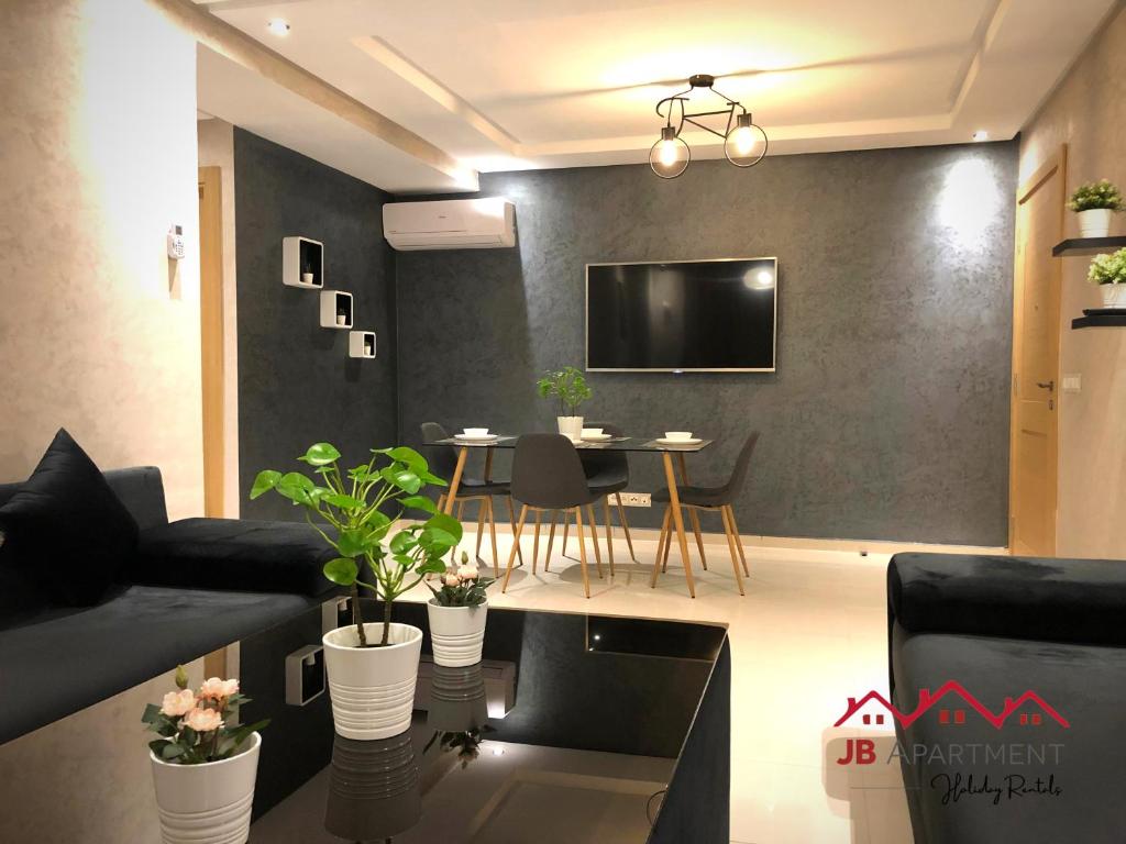 a living room with a table and a tv on a wall at JB Apartment -B18- in Kenitra