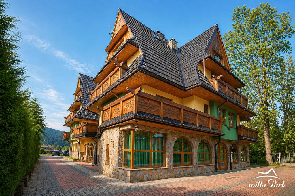 a large building with a gambrel roof on a street at Willa Park in Zakopane