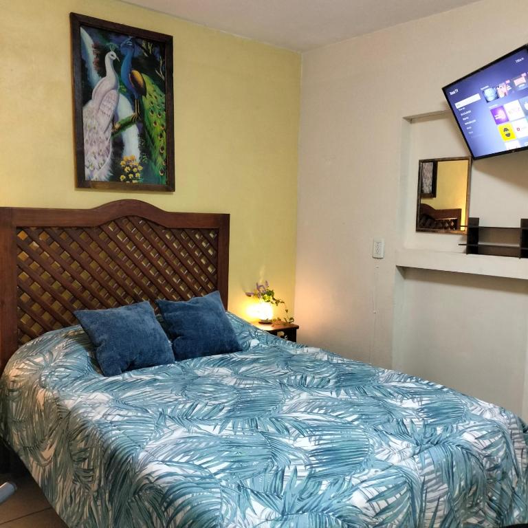 a bedroom with a bed with blue pillows and a tv at HabitacionSUPER4 2 personas Casa SFco in Zacatlán